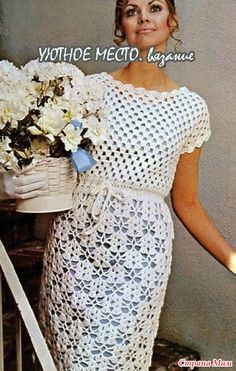 a woman in a white crochet dress holding a basket with flowers on it