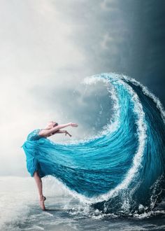 a woman is standing in the water with her arms spread out and she has long blue hair