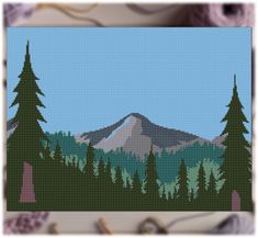 the cross stitch pattern shows a mountain with trees in front of it and a blue sky above