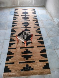 a black and tan rug with an ottoman on it