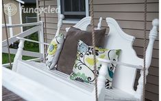 a white porch swing with pillows on it