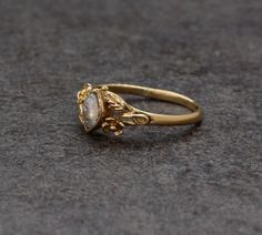 a gold ring with an oval stone in the center on a gray surface, close up