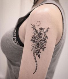 a woman with a flower tattoo on her arm and the moon behind her back shoulder