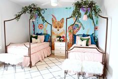 two beds in a room with colorful wallpaper and paintings on the walls behind them