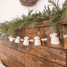 christmas decorations are hanging on the side of a wooden wall with pine needles and white pom poms