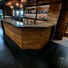 an empty bar with several bottles on the wall and lights hanging from the ceiling above it