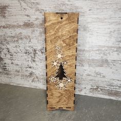 a wooden box with a christmas tree cut out on the side and snowflakes around it