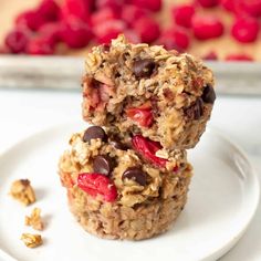 two oatmeal muffins on a plate with raspberries and chocolate chips