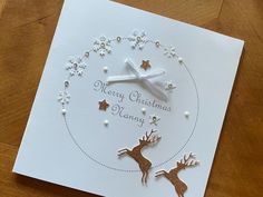 a christmas card with reindeers and stars in the middle, on a wooden table