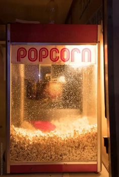 a popcorn machine sitting on top of a floor next to a window filled with popcorn