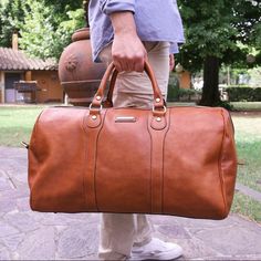 Pack for your next adventure in style with the Oslo Italian leather duffel bag.   Experience the timeless beauty of Italian craftsmanship with the Oslo cowhide weekender bag - the ultimate weekend companion for the modern traveler. Handcrafted in Italy from the finest full grain leather with a chic matte finish, this holdall exudes elegance and sophistication. With its spacious interior and soft structure, the Oslo is perfect for carrying all your essentials for a weekend getaway or a special occasion. The cotton lining and metal feet on the bottom offer added protection for your belongings, while the detachable and adjustable leather shoulder strap allows for comfortable carrying. The Oslo also features brushed brass-toned or silver-toned hardware (depending on the color of the bag), incl Classic Leather-lined Luggage For Weekend Trips, Luxury Weekender Bag With Leather Handles For Weekend Trips, Elegant Weekend Tote Duffle Bag, Elegant Tote Duffle Bag For Weekend Trips, Elegant Tote Weekender Bag For Weekend Trips, Elegant Tote Weekender Bag, Elegant Weekender Tote Bag For Weekend Trips, Elegant Cognac Travel Bag With Luggage Sleeve, Classic Cognac Weekender Bag With Leather Lining