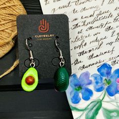 Get ready to swoon over these cute and charming earrings shaped like avocados! Handmade with care by skilled artisans, these clay beauties are out of this world. They're sure to turn heads and add a touch of chic to your outfit. These Mexican earrings offer a mix of traditional and modern styles, perfect for those looking for something one-of-a-kind. Get your hands on some CLAYWELRY™ and experience the joy of wearing something truly special. MATERIAL(S): All our earrings are created using natural earth terracotta/white clay. High quality acrylic paint, brass metal alloy ear wires and findings, and clear acrylic coat sealer. TECHNIQUE: 100% Handmade and Hand Painted. Superb attention to detail. Masterfully and artfully designed by experienced and talented Mexican artisans so you can enjoy t Fiesta Clay Earrings, Avocado Clay Earrings, Clay Taco Earrings, Avocado Keychain, Taco Earrings, Mexican Earrings, Paint Brass, Artfully Designed, Natural Earth