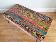 a multicolored wooden bench sitting on top of a hard wood floor