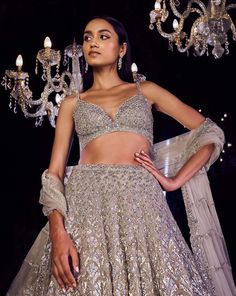 This lehenga set features platinum cut sequin and crystal embellishment in a cascade motif pattern. The ensemble is paired with a criss-cross back and fully embroidered net dupatta.From Seema Gujral's Tuscan Summer collection. DELIVERY TIMEPlease allow 4 months for your outfit to arrive. FABRIC DETAILSNet Professional cleaning only. Luxury Designer Silver Lehenga, Designer Silver Sequined Lehenga, Luxury Silver Sequined Lehenga, Festive Silver Embellished Lehenga, Crystal Lehenga, Silver Cutdana Lehenga, Tuscan Summer, Seema Gujral, Motif Pattern