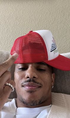 a man wearing a red and white hat sitting on top of a couch next to a wall