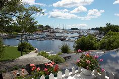 boats are docked in the water near a white picket fence and flower potted planters