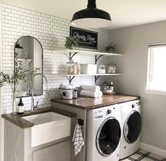 a washer and dryer in a room with white brick walls, wood counter tops and open shelving