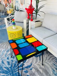 a living room filled with lots of furniture and colorful tables on top of carpeted flooring