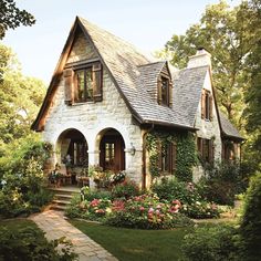 a house that is surrounded by flowers and greenery