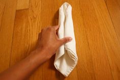 a hand holding a napkin on top of a wooden floor