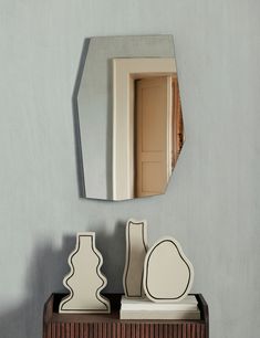 a mirror sitting on top of a wooden cabinet next to a vase and other items