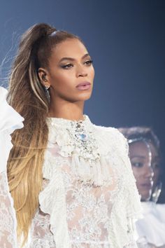 a woman with long blonde hair wearing a white dress and earrings on her head, looking off to the side