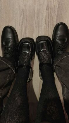 three pairs of black shoes with lace on them sitting in front of a wooden wall