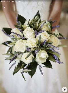 a bridal holding a bouquet of white roses and lavenders on her wedding day