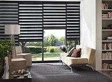 a living room filled with furniture and a large window covered in black shuttered shades