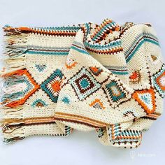 a crocheted blanket with fringes on it sitting on a white table top