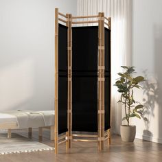 a bamboo room divider in front of a white wall with a potted plant next to it