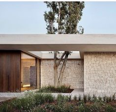 an exterior view of a modern home with trees and shrubs in the foreground,