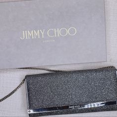 Jimmy Choo. Inject Milla Anthracite Instant Elegance Into Evening Ensembles With The Emmie Clutch Bag From Jimmy Choo With An Iridescent Glitter Exterior. Structured And Compact, The Slim Silhouette Opens Via An Asymmetric Flap Front To A Smooth Interior With Practical Card Slots And A Zipped Pouch, Keeping Money And Essentials Housed Safely As It Swings From The Optional Chain Strap. Evening Bag With Silver-tone Logo Plaque In Metallic Silver, Metallic Silver Evening Bag With Logo Plaque, Metallic Silver Evening Bags With Silver-tone Logo Plaque, Silver Evening Bag With Silver-tone Logo Plaque, Silver Party Bags With Silver-tone Logo Plaque, Metallic Bags With Silver-tone Logo Plaque For Formal Occasion, Luxury Metallic Silver Bag For Formal Occasions, Designer Evening Bags With Silver Accents, Luxury Metallic Silver Bags For Party