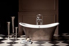 a bath tub sitting on top of a black and white checkered floor next to candles