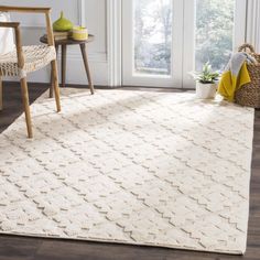 a white rug with an intricate design on the floor in front of a chair and table