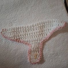 a crocheted piece of cloth is laying on top of a white sheet with pink trim