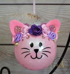 a pink cat ornament with purple flowers on it's head and ears