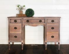 a wooden desk with drawers and a potted plant on top