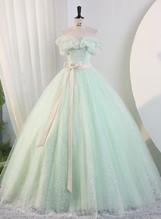 Anotherworldly charm characterizes this beautiful Quinceanera dress, crafted to make you feel like a true princess. The soft, pastel green fabric brings a sense of serenity and grace, while the off-shoulder design with delicate ruffles adds a touch of ethereal beauty. The bodice is adorned with subtle floral appliques, enhancing its romantic appeal. A satin ribbon at the waist accentuates the silhouette, adding a classic, elegant detail. The voluminous skirt, composed of multiple layers of airy tulle, creates a dreamy, floating effect as you move. This gown is meticulously designed for both comfort and visual impact, ensuring you look and feel your best throughout the celebration. Every aspect of this dress, from the intricate embellishments to the flowing skirt, is designed to make your Q Princess Style Green Dress For Quinceanera, Green Princess Tulle Quinceanera Dress, Princess Green Ball Gown For Quinceanera, Princess Style Green Ball Gown For Quinceanera, Green Tulle Quinceanera Dress With Sweetheart Neckline, Green Quinceanera Dress With Sweetheart Neckline, Green Princess Style Dress For Debutante Ball, Princess Style Quinceanera Dress With Ruffles, Elegant Green Princess Dress For Prom