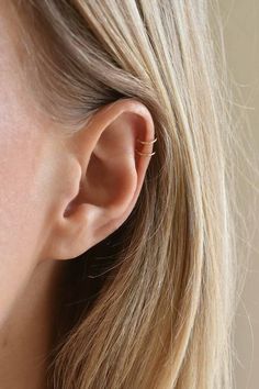 a close up of a woman's ear wearing gold earrings