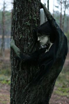 a creepy looking person climbing up the side of a tree