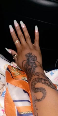 a woman's arm with tattoos on it and her hand resting on the pillow