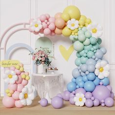 balloons and flowers are arranged in the shape of a rainbow arch for a birthday party