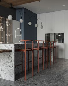 a modern kitchen with marble counter tops and wooden barstools, along with hanging lights