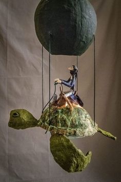 a sculpture of a woman sitting on top of a turtle next to a green ball