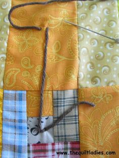 an orange and yellow patchwork quilt with twine on it's end, next to a piece of string