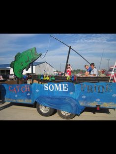 people are riding in the back of a truck with a fish sign on it's side