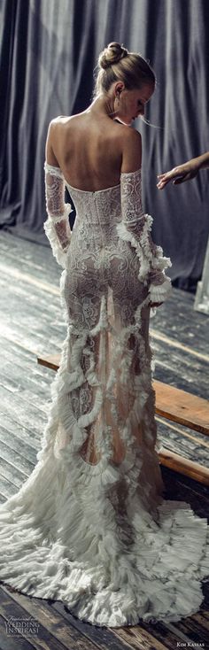 a woman in a white wedding dress standing on a wooden floor with her back to the camera