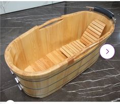 a wooden bathtub sitting on top of a marble floor next to a black handle