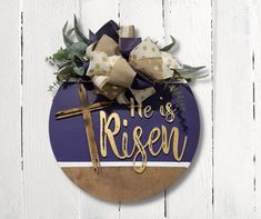 a wooden plaque with a cross and flowers on it that says he is risen in gold lettering